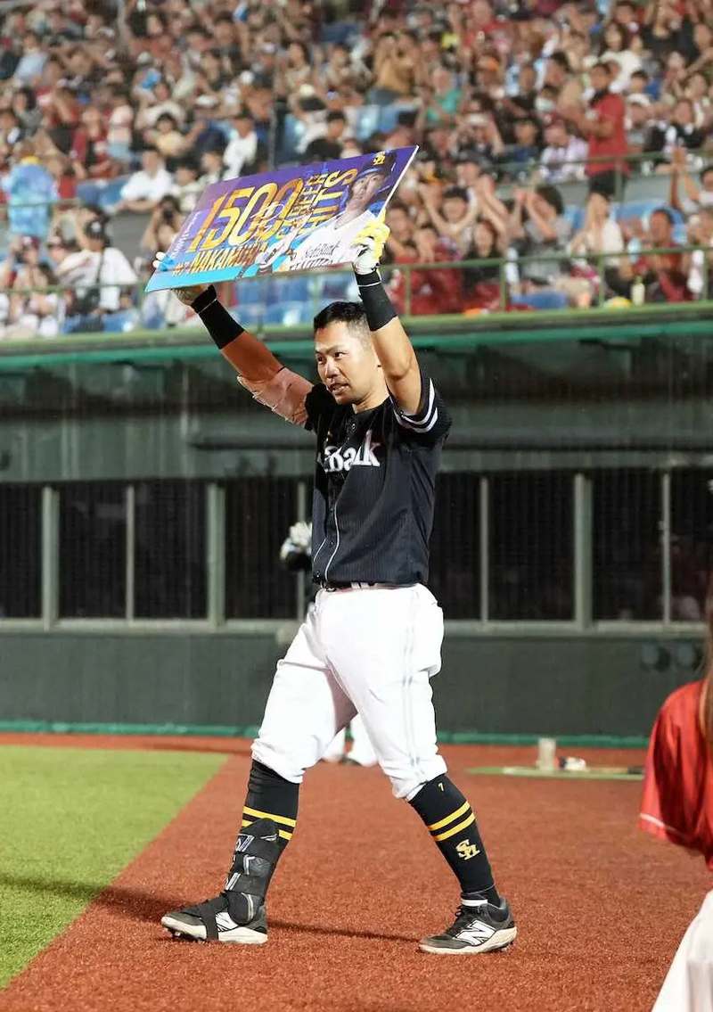 通算1500安打の記念ボードを掲げる中村晃さん
